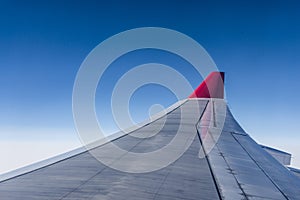 Wing of airplane from Air in the sky winglet red colored airline blue sky clouds