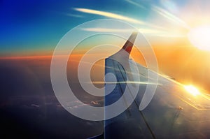 Wing of the airplane in flight in sunrise beams