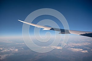 Wing of airplane flying above in blue sky on sunny day