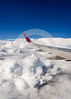 Wing of airplane flying above clouds