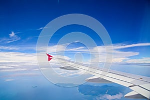 Wing of airplane flying above the clouds in the blue sky