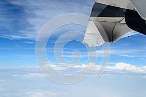 Wing of airplane flying above the clouds and blue sky
