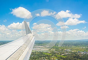 Wing of an airplane flying above the clouds and the city
