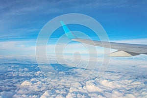 Wing of an airplane flying above the clouds. Looks at the sky from the window of the plane, using airtransport to travel