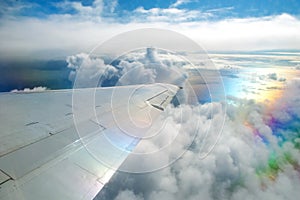 Wing of airplane flying above clouds in the sky