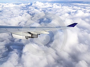 Wing of airplane flying above the clouds in the sky