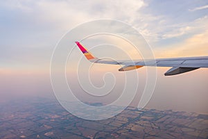 Wing of an airplane flying above the clouds at sunset .