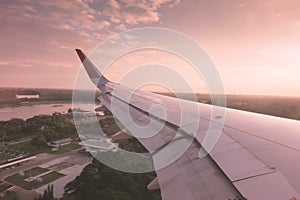 Wing of an airplane flying above the clouds at sunset . ( Filter