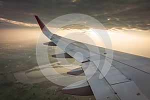 Wing of an airplane flying above the clouds at sunset . ( Filter