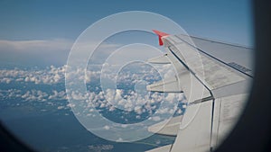 Wing of airplane flying above clouds. View from the window of the plane.