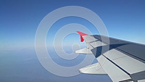 Wing of an airplane flying above the morning clouds. Aircraft wing in the sky, looking through the window