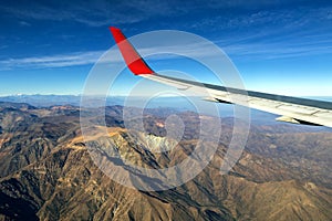 Wing of an airplane flying above the morning clouds and Andean mountain range