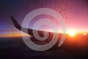 Wing of an airplane flying in backlight at sunset