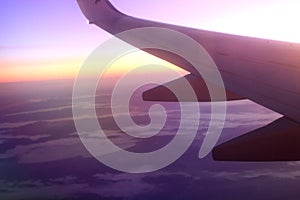 Wing of an airplane flying in backlight at sunset