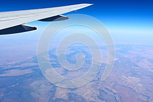 Wing of airplane flying over Australian outback.