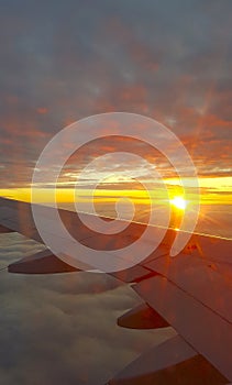 Wing of an airplane flying over the sunset clouds