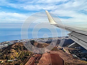 Wing of an airplane flying over Tenerife on the backdrop of the Atlantic Ocean