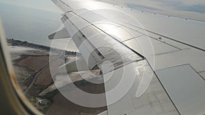 Wing of an airplane, passenger s view. Looking through the window of a plane on its shining wing