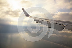 Wing of airplane with rays through clouds