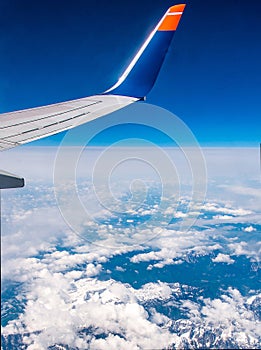 Wing of airplane in the sky red winglet blue sky clouds