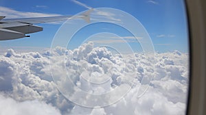 wing of airplane and the white clouds from above seen from the window porthole