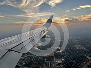 The wing of a commercial airline airplane while flying high in the sky over Dallas Texas on a trael vacation