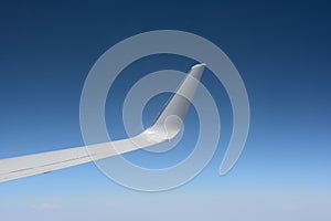 Wing of highly flying plane against the background of the clear blue sky