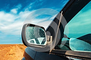 Wing mirror of a car on dirt country road