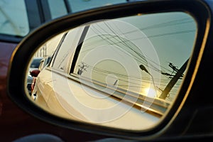 A wing mirror of a car with sun light reflection and blur street area background