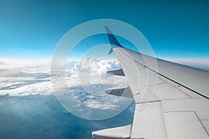 A wing of a modern passenger airplane above the clouds. International cargo transportation, air travel, transport. Copy space