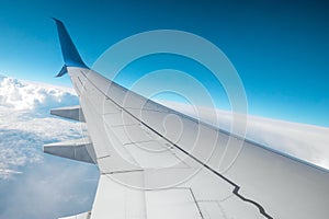 A wing of a modern passenger airplane above the clouds. International cargo transportation, air travel, transport. Copy space