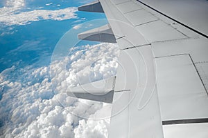 A wing of a modern passenger airplane above the clouds. International cargo transportation, air travel, transport. Copy space