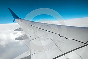 A wing of a modern passenger airplane above the clouds. International cargo transportation, air travel, transport. Copy space