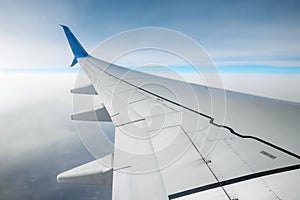 A wing of a modern passenger airplane above the clouds. International cargo transportation, air travel, transport. Copy space