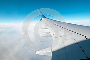 A wing of a modern passenger airplane above the clouds. International cargo transportation, air travel, transport. Copy space