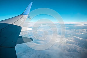 A wing of a modern passenger airplane above the clouds. International cargo transportation, air travel, transport. Copy space