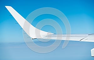 Wing of plane over white clouds. Airplane flying on blue sky. Scenic view from airplane window. Commercial airline flight. Plane