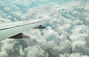 Wing of plane over white clouds. Airplane flying on blue sky. Scenic view from airplane window. Commercial airline flight. Plane