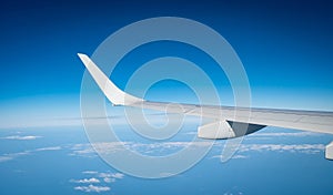 Wing of plane over white clouds. Airplane flying on blue sky. Scenic view from airplane window. Commercial airline flight. Plane