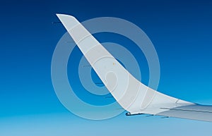 Wing of plane over white clouds. Airplane flying on clear blue sky. Scenic view from airplane window. Commercial airline flight.