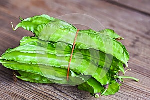 Winged Bean on wooden background, Psophocarpus tetragonolobus - Green winged or Four angle beans