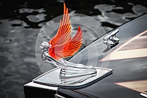 Winged figurehead made of chrome and a translucent orange-red material mounted on bow of classic wooden speedboat