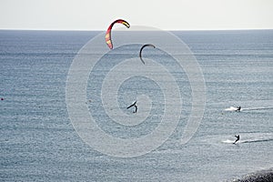 A wingfoiler and kiteboarders ride their boards on the waves of the Atlantic Ocean in Matas Bay. Costa Calma, Spain. photo