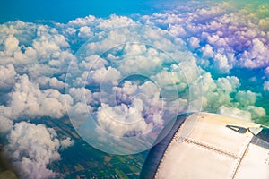 wings of airplane during the flight look from the passenger window. There are white clouds in the blue sky