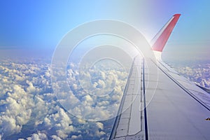 wings of airplane during the flight look from the passenger window. There are white clouds in the blue sky