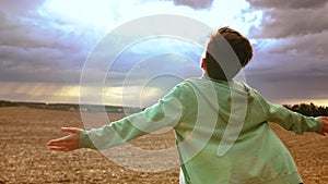 Wings of Wonder: Boy Embracing the Sky Amidst Stormy Clouds with Sunrays Peeking Through, boy spreads his arms like a