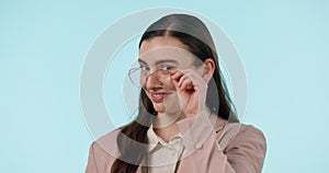 Wink, flirt and face of woman with glasses in studio with confidence, good mood or gesture on blue background. Nerd