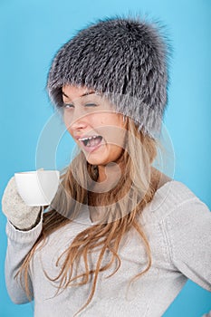 Winked woman holding a cup with hot drinks photo