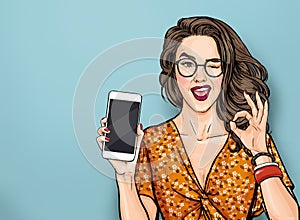 Winking woman in glasses showing smart pone and OK sign. Pop art girl holding phone. Digital advertisement female model