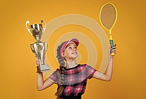 winner child with racquet and champions cup. teen girl win tennis championship. sport. tennis or badminton player